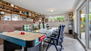 Een kamer met een tafelvoetbaltafel, een bakstenen muur met planken en een groot raam.