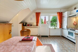 Une cuisine de taille réduite comprenant un coin repas, un radiateur et une fenêtre avec des rideaux.