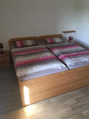 Una cama doble con estructura de madera y colcha a rayas.