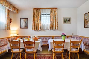 A dining area with a table set for four, a bench, and a window with curtains. - Landhaus Strell with Garden and Terrace (Bad Griesbach im Rottal)