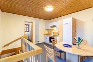 Una cocina con armarios de madera, estufa y comedor con mesa y sillas.
