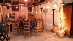 A rustic room with a dining table, chairs, a chandelier, and a brick wall.