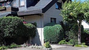 Uma casa de dois andares com telhado inclinado, fachada de tijolos e um jardim bem cuidado.