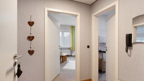 Um corredor com piso de madeira, uma porta decorada com formato de coração e um telefone na parede.