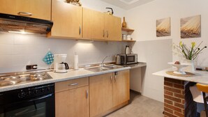 Uma cozinha moderna com armários de madeira, forno embutido, cafeteira e micro-ondas.