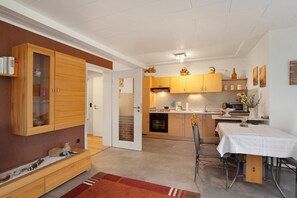 A compact kitchen with wooden cabinets, a dining area with a table, and a built-in bench with storage.