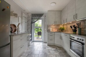 A modern kitchen with grey cabinets, a built-in oven, and a dining area visible through a glass door. - holiday home 'Hus An Diek' with Shared Garden and Wi-Fi (Hillgroven)