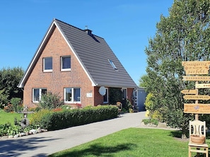Une maison à deux étages, dotée d’un toit en pente, d’une façade en briques et d’un chemin menant à l’entrée.
