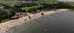 An aerial view of a beach with a large number of people, boats, and a stadium in the background.