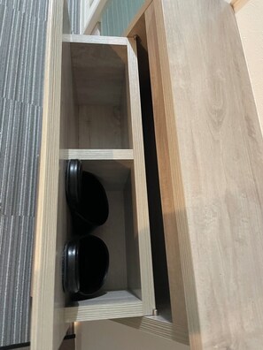 A wooden cabinet with three shelves, each containing a black object. - HJ PLACE TAKANAWA by Tranova (Tokyo)