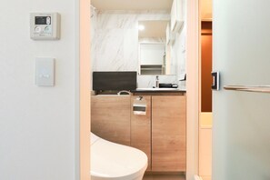 A compact bathroom with a toilet, sink, and mirror. - HJ PLACE TAKANAWA by Tranova (Tokyo)