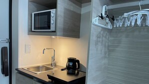 A modern kitchen with a stainless steel sink, a microwave, and a coffee maker on the countertop. - HJ PLACE TAKANAWA by Tranova (Tokyo)