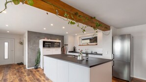 Une cuisine moderne dotée d’un îlot central, d’appareils électroménagers intégrés et d’un plafond en bois.