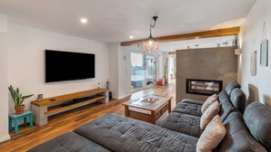 Un salon moderne doté d’un téléviseur à écran plat, d’une cheminée et d’un grand canapé.