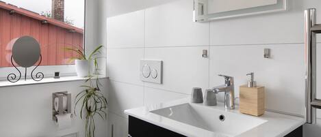 Un baño moderno con un lavabo grande, espejo y retrete.