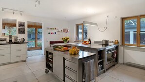 A modern kitchen with a central island, built-in oven, and a dining area with a view.