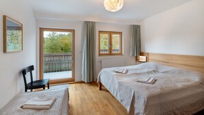 A bedroom with two beds, a chair, a window, and a ceiling light fixture.
