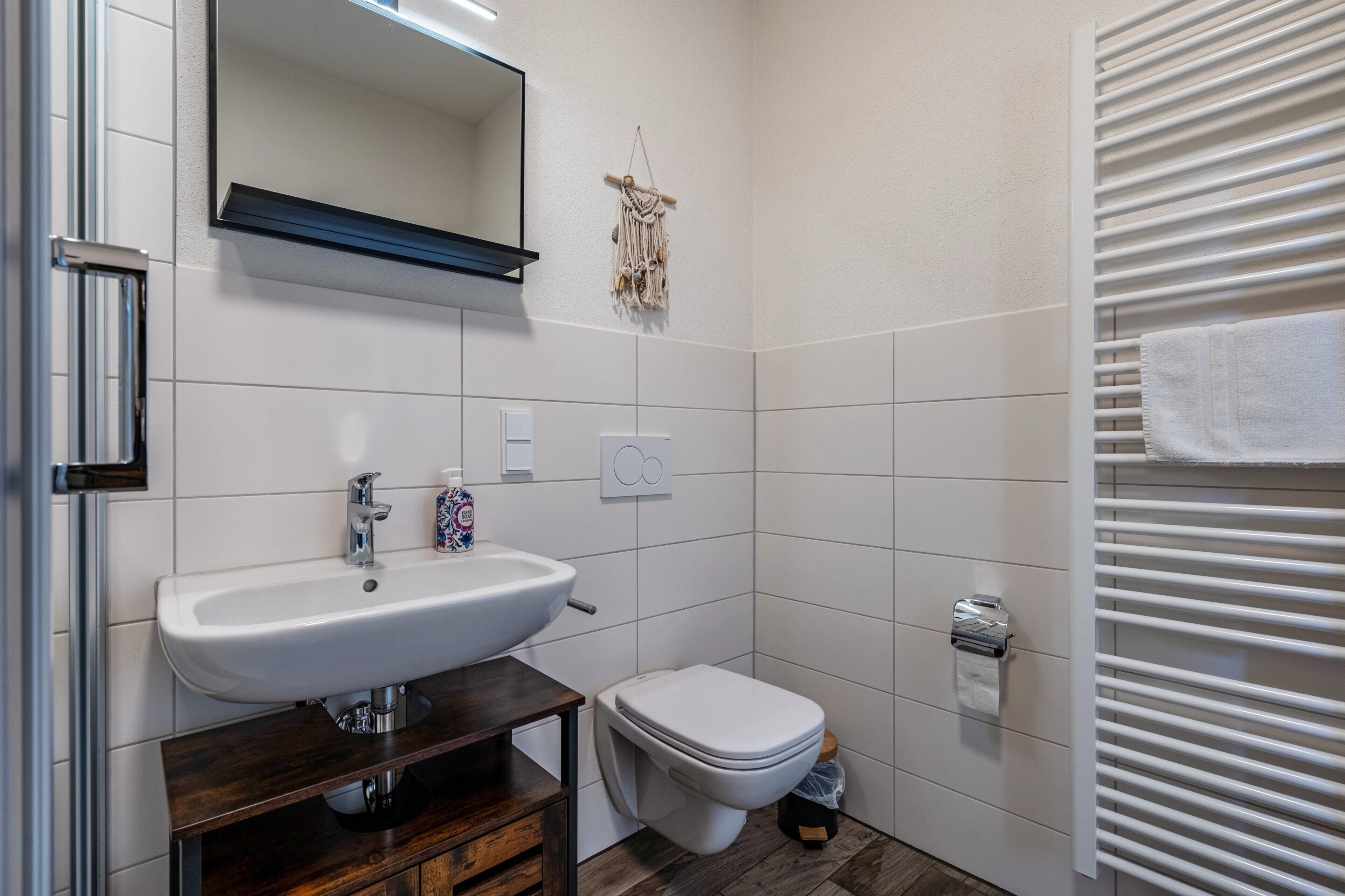 Ein Badezimmer mit weißem Waschbecken, Spiegel, Toilette und Handtuchhalter.