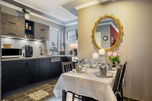 Une cuisine moderne avec des meubles de couleur sombre, une table à manger dressée pour un repas et un miroir décoratif accroché au mur.