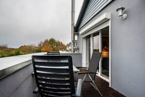 Ein Balkon mit Tisch und Stühlen, Blick auf die Umgebung und ein Hauseingang.