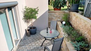 Eine Terrasse mit rundem Tisch und Stühlen, einem Blumentopf und einer Backsteinmauer.