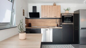 Eine moderne Küche mit Holzschränken, einem Einbauofen, einer Spülmaschine und einem Kühlschrank.
