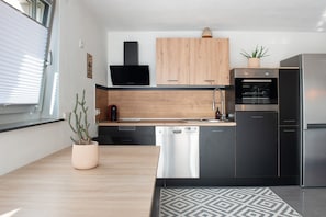 Een moderne keuken met houten kastjes, een inbouwoven, een vaatwasser en een koelkast.