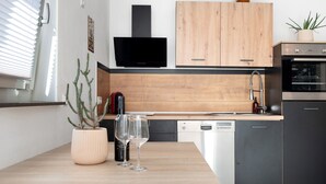 Eine moderne Küche mit Holzschränken, einer schwarzen Dunstabzugshaube, einem Geschirrspüler und einem Einbauofen.