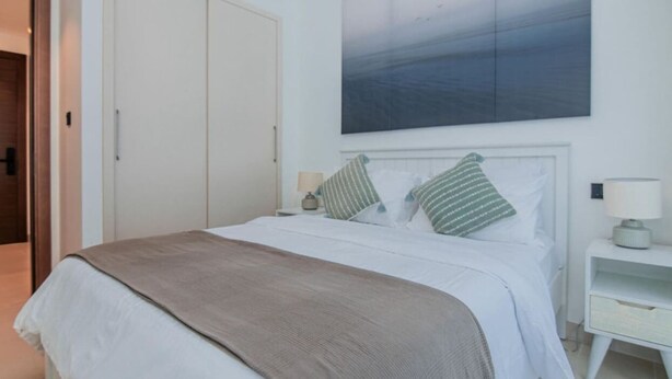 Een slaapkamer met een bed, nachtkastjes en een schilderij aan de wand.