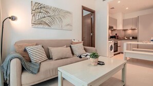 Een moderne woonkamer met een bank, een salontafel en een keuken op de achtergrond.
