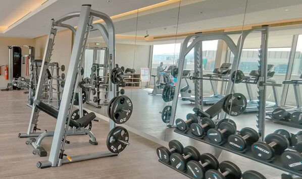 Une salle de sport équipée de divers appareils d’exercice, notamment des machines de musculation et des haltères.