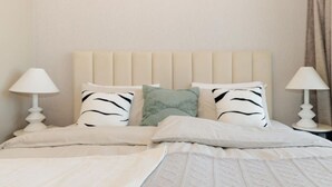 Una cama con cabecera, dos lámparas de noche y almohadas con estampado de cebra.