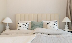En säng med en sänggavel, två sänglampor och kuddar med zebrasträck.