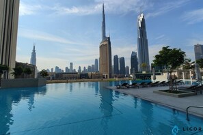 A swimming pool with a city skyline in the background, including a prominent skyscraper.