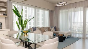 Una sala de estar moderna con una mesa de vidrio, un juego de sofá y una planta grande.