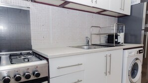 A kitchen with a gas stove, a washing machine, and a sink. - Prime Spacious 2 BR Apt, Burj Khalifa & Canal View (Dubai)