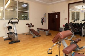 Une salle de sport équipée de matériel d’exercice, d’un banc et d’un miroir.