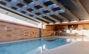 An indoor swimming pool with a tiled wall and a ceiling with geometric patterns. - Prime Spacious 2 BR Apt, Burj Khalifa & Canal View (Dubai)