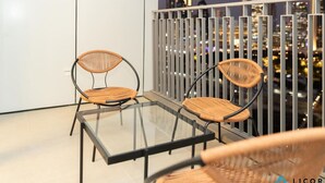 A balcony with two wicker chairs and a glass table, overlooking a cityscape at night. - Stylish 2BR Apt with pool view of Burj Khalifa - Downtown Views (Dubai)