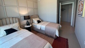 A hotel room with two beds, a nightstand, a lamp, and a red rug. - Stylish 2BR Apt with pool view of Burj Khalifa - Downtown Views (Dubai)