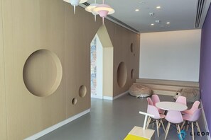 A modern interior with a wooden wall, circular cutouts, a round table with chairs, and a large window.
