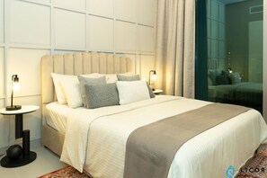 A modern bedroom with a large bed, two bedside tables, and a view of the city through a glass wall.