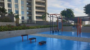 An outdoor area with a blue floor, two benches, and a climbing structure. - Stylish 2BR Apt with pool view of Burj Khalifa - Downtown Views (Dubai)
