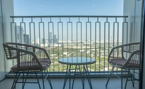 En balkon med to fletstole og et lille rundt bord, der udover en byudsigt.