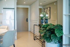 A modern hotel room with a dining area, a potted plant, and a door leading to another room.