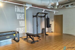 A gym with a bench, a squat rack, and a punching bag. - Unveil Downtown Luxury 1BR Majestic Skyline Views - Downtown Views ll (Dubai)
