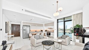 Un appartement moderne comprenant un salon, un coin repas, une cuisine et une grande fenêtre donnant sur la ville.