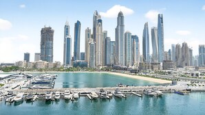 Un port de plaisance où sont amarrés de nombreux yachts, entouré d’une vue urbaine avec des gratte-ciel modernes.