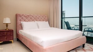 Una camera d'albergo con un letto grande, un comodino, una lampada e vista sulla città attraverso ampie finestre.