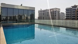Una piscina sul tetto con acqua cristallina e limpida, circondata da edifici moderni.